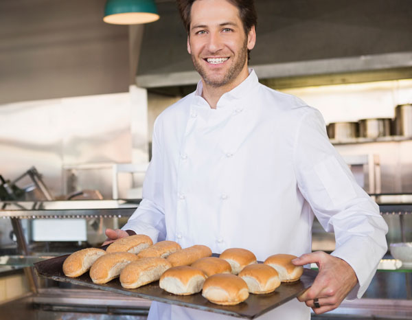 Chef in restaurant carrying a tray of buns and rolls